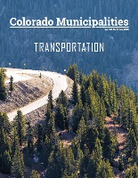 cover of colorado municipalities July 2025 magazine picturing a mountain road looking up hill, past evergreen trees to a turn with mountain view